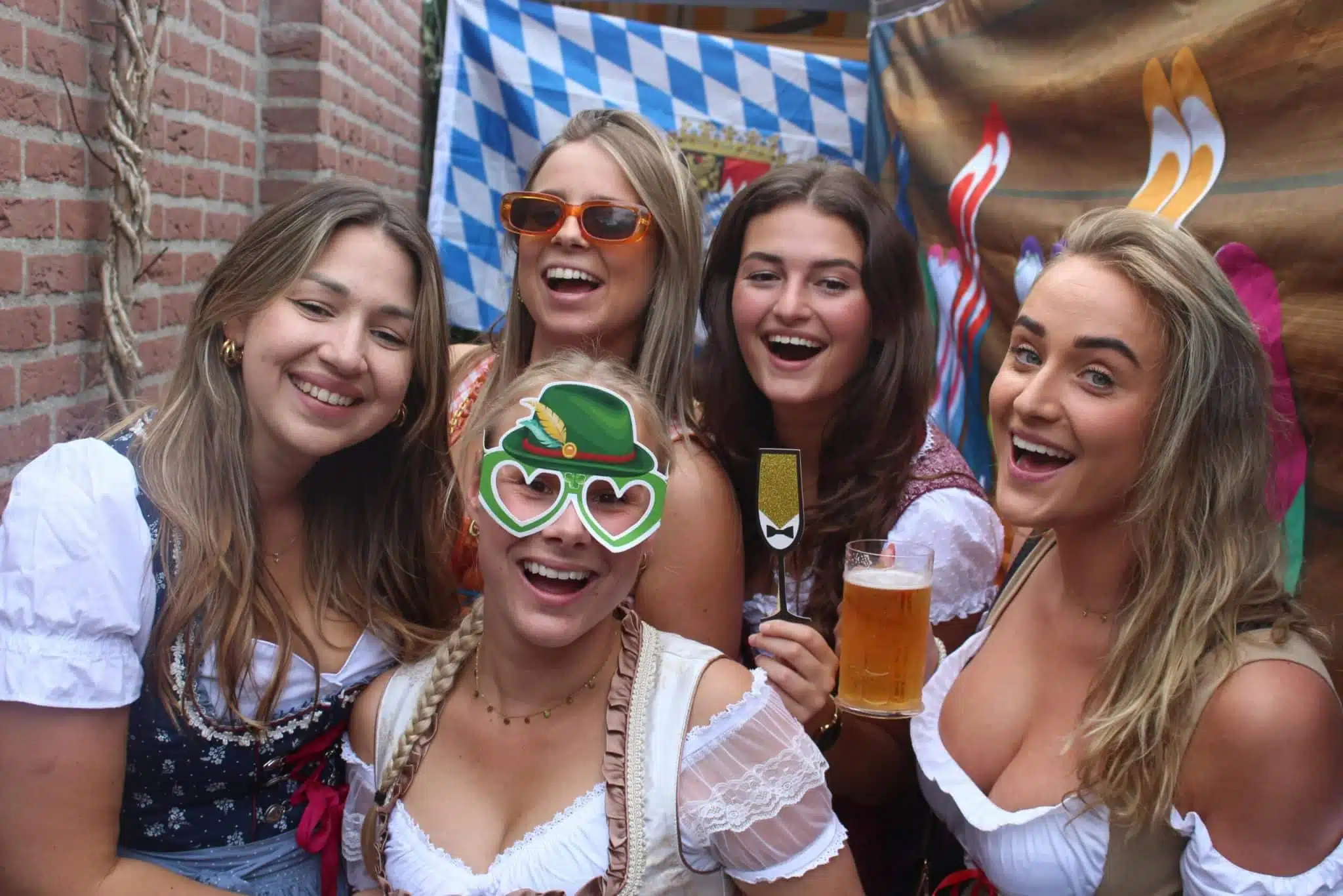 Lachende gasten in dirndl met photobooth-props op een Oktoberfest-feest